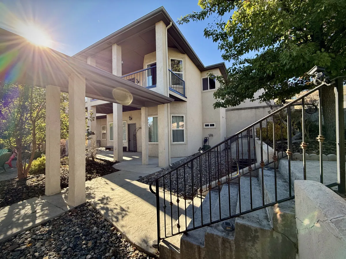 The exterior of the estate features a grand entrance with pillars, an elegant balcony, and a sweeping staircase. The space evokes a sense of openness and luxury, ideal for both socializing outdoors and appreciating the landscaped yard.