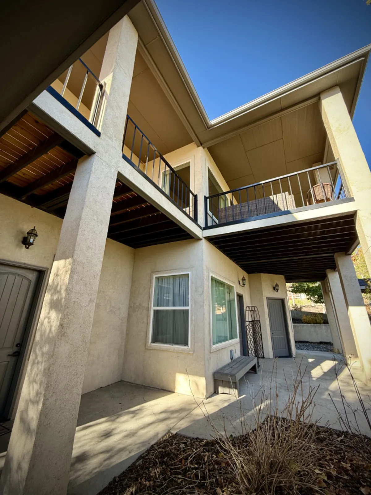 This exterior image captures a spacious balcony, large windows, an entrance door, and a welcoming patio area with railings. The scene is bright and inviting, suggesting a perfect spot for relaxing outdoors or entertaining guests while enjoying scenic views.