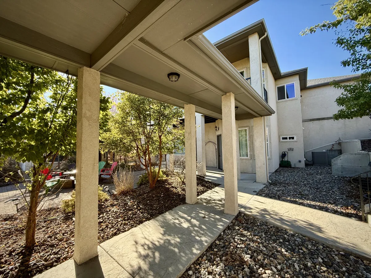 A serene estate entrance featuring a welcoming pathway, stately columns, lush greenery, and an adjoining patio. The layout hints at the venue's event-friendly design, seamless indoor-outdoor flow, and multiple gathering zones.