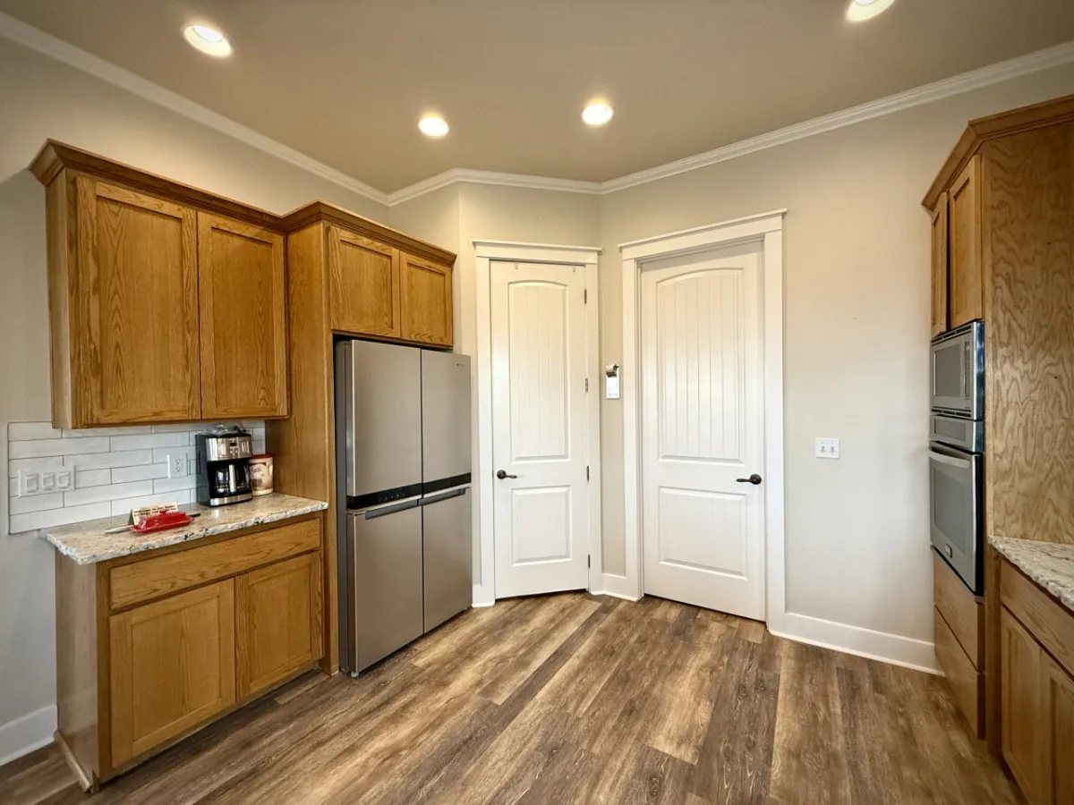 A view of the kitchen showing elegant cabinetry, a sleek stainless steel refrigerator, granite countertops, and a well-appointed coffee station. The ambiance is warm and welcoming, ideal for entertaining guests or enjoying family meals.