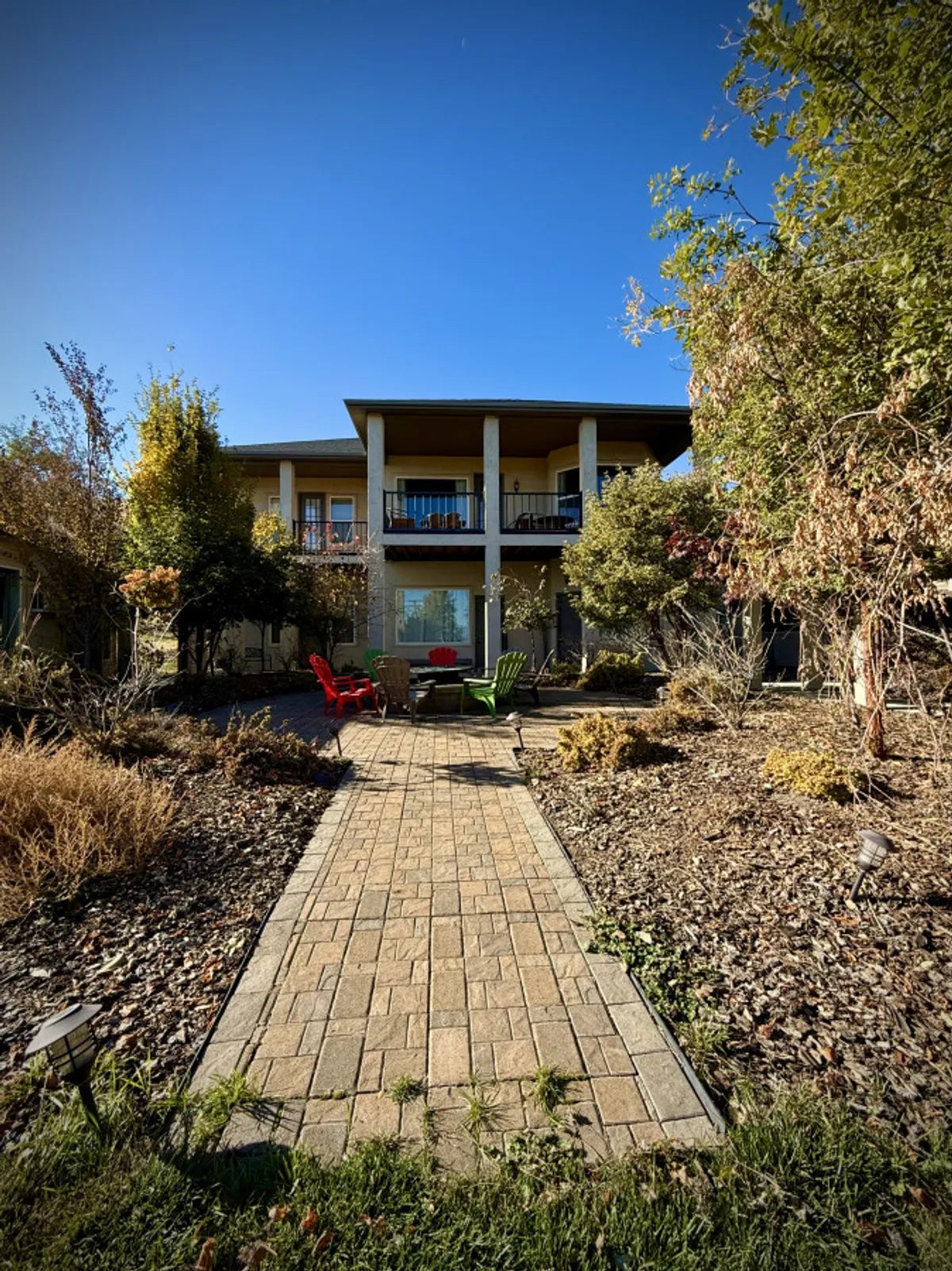 A welcoming exterior view of the house with two colorful chairs on a pathway leading to a balcony. The inviting setup suggests a space for friends or family to gather after a day on the slopes, with opportunities to unwind and enjoy the crisp winter air.