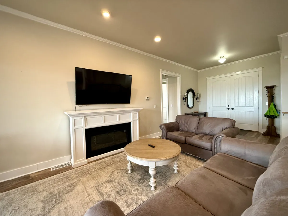 A cozy living room vignette featuring a sofa, coffee table, television, inviting fireplace, and doors that suggest a flow to other parts of the home. The setup is perfect for movie marathons or intimate gatherings.