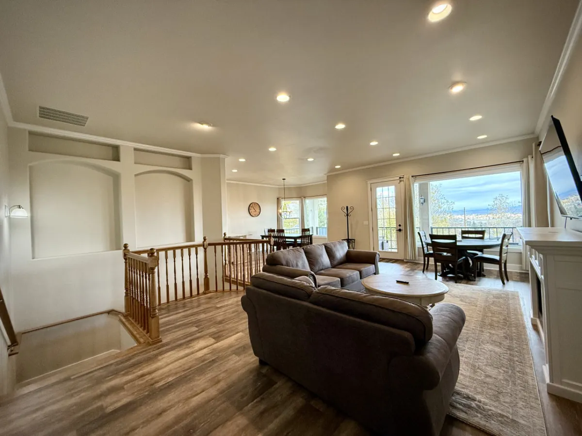 A cozy living area featuring a sofa, dining space, large windows, and an inviting fireplace. The space is ideal for sharing warm drinks, socializing, and watching the sunrise—perfect for winding down after an active day.